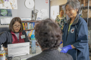 Photo of 4 people, 3 helping at the client assistance registration table.