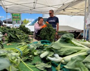 Photo of Shane our warehouse manager and a market vendor with vegetables.